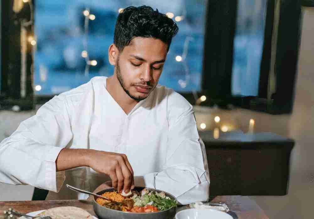 man eating healthy bowl of food with his hands 